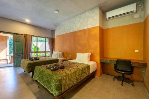 a bedroom with two beds and a desk and a chair at Sun Sang Eco Retreats in Tabanan