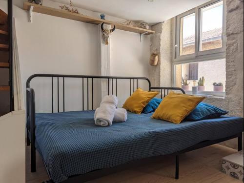 - un lit avec des oreillers jaunes et bleus dans l'établissement Charmant loft atypique à Palavas, à Palavas-les-Flots