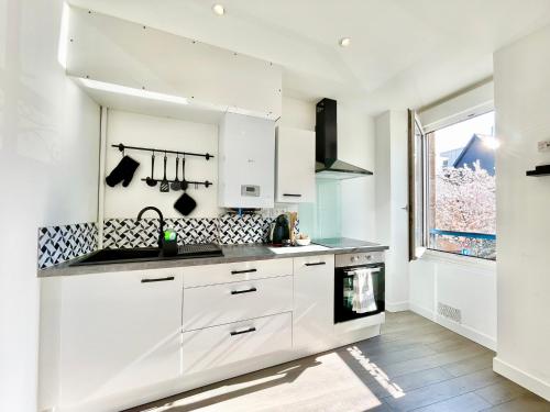 une cuisine blanche avec des armoires blanches et une fenêtre dans l'établissement Le Turquoise I Grand T2 lumineux I Proche Gare, à Lorient