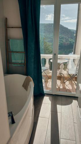 a bathroom with a tub and a view of a balcony at Ma villa au bord de l'eau in Miremont
