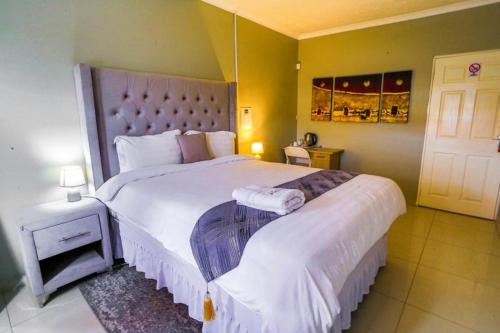 a bedroom with a large bed with white sheets at Classique B&B Jwaneng in Jwaneng
