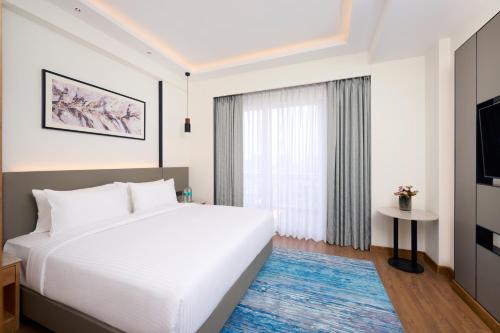 a bedroom with a large white bed and a window at Iris Sarovar Portico in Gurgaon