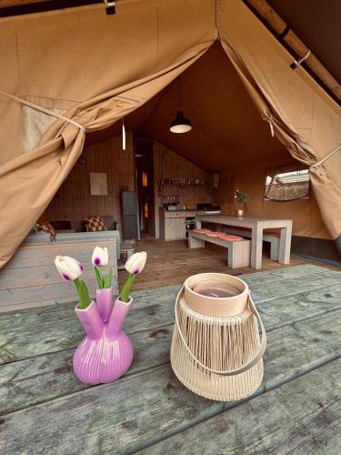 a tent with a vase with flowers in it at Glamping Holten luxe safaritent 2 in Holten