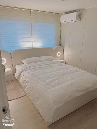 a white bed in a room with a window at Jaha 79 in Seoul