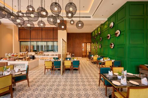 a restaurant with green walls and tables and chairs at Iris Sarovar Portico in Gurgaon