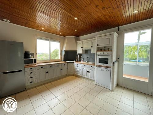 une cuisine avec des armoires blanches et un plafond en bois dans l'établissement Gîte rustique dans le Marais breton vendéen, proche plages - FR-1-426-575, à Sallertaine