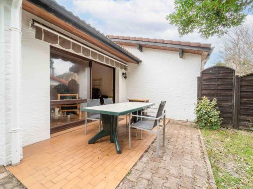 un patio avec une table et des chaises devant une maison dans l'établissement Maisonnette à Mimizan Plage, 6 Pers, Proche Océan, Parking Inclus - FR-1-50-167, à Mimizan