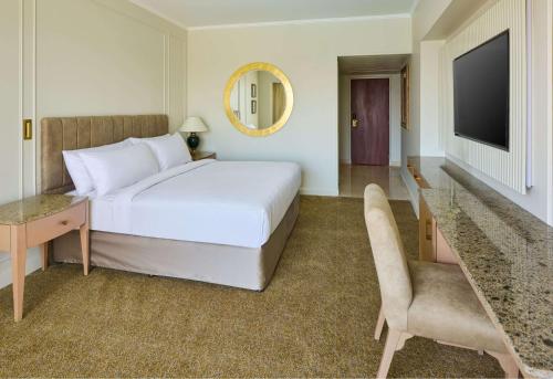 a bedroom with a bed and a desk and a television at Hilton Cairo Grand Nile in Cairo