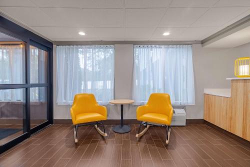 two yellow chairs and a table in a room with windows at Spark by Hilton Clarks Summit in Clarks Summit