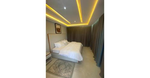 a bedroom with a white bed and a ceiling with lights at Home Xperience Luxury Apartments in Limbe
