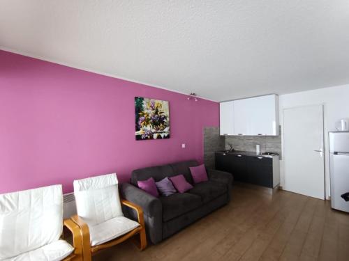 - un salon avec un canapé et un mur pourpre dans l'établissement Résidence Chamoisiere - Beau Studio 4 pers terrasse - Proche des pistes MAE-8714, à Montgenèvre
