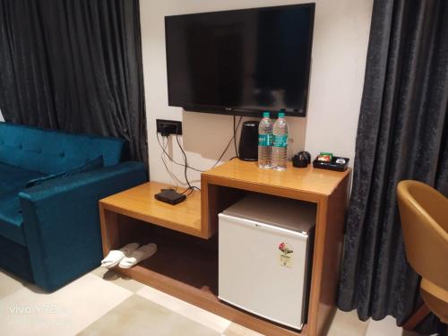 a living room with a tv and a small refrigerator at Hotel Prince Garden Daman in Daman