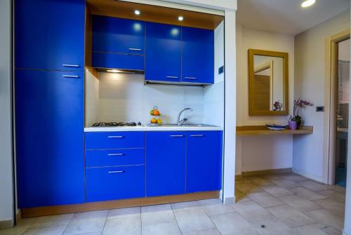a kitchen with blue cabinets and a sink at Hotel Villaggio Old River in Capo Vaticano