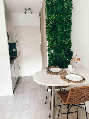 une table blanche avec des chaises et un mur vert dans l'établissement Studio cosy Ile de Nantes proche tram ligne 2 et 3, à Nantes