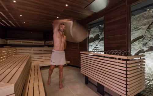 a man standing in a sauna talking on a cell phone at Schenna Resort in Schenna