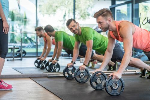 a group of men in a gym working out with weights at Schenna Resort in Schenna