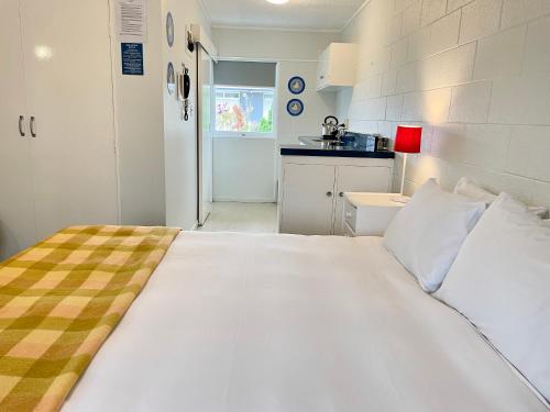 a large white bed in a room with a kitchen at Mount Eden Motel in Auckland