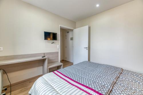 a bedroom with a bed and a tv on a wall at Logis Les Forges in Arvillard