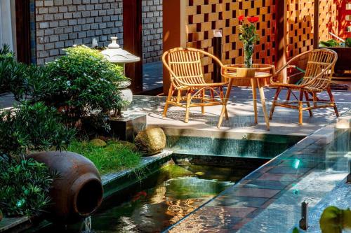 a patio with a table and chairs and a pond at Nana Homestay & Villa Apartment in Thôn Trường Giang