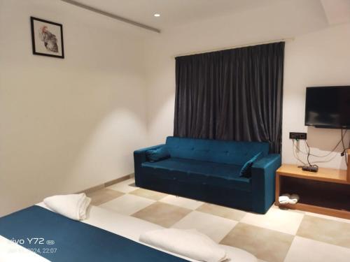 a living room with a blue couch and a television at Hotel Prince Garden Daman in Daman