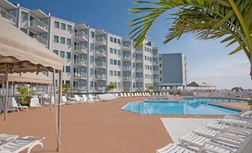 un complejo con piscina, sillas y un edificio en El Coronado Resort, en Wildwood Crest