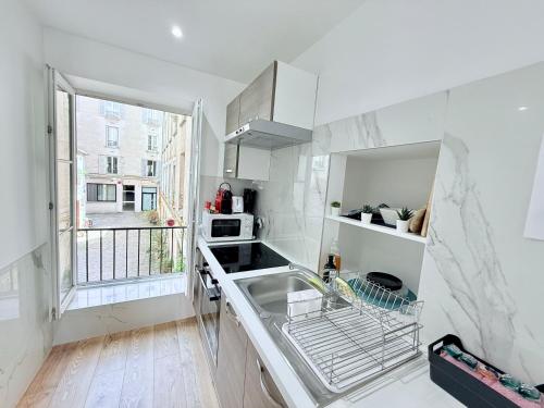 une cuisine blanche avec un évier et une fenêtre dans l'établissement Magnifique 2 pièces refait à neuf - Parking, à Paris