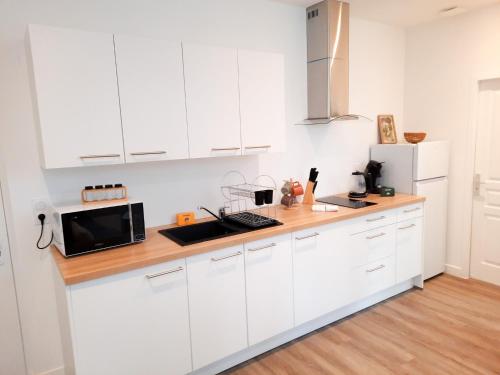 une cuisine blanche avec des armoires blanches et un micro-ondes dans l'établissement Le Foch - Apt 4 Personnes, 1 ch, Proche Gare, à Dijon