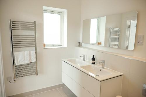 a white bathroom with a sink and a mirror at Kerrek Lodge in Falmouth
