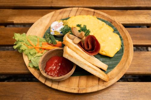 a plate of food with a sandwich and other foods at Bobocabin Umarato, Sumba in Waikabubak