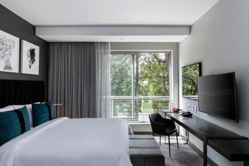 una camera da letto con un letto, una scrivania e una grande finestra di The Capital Empire a Johannesburg