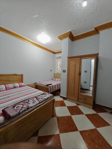 Un dormitorio con dos camas y suelo de cuadros. en See you soon الشاطئ الأزرق, en Marsa Matruh