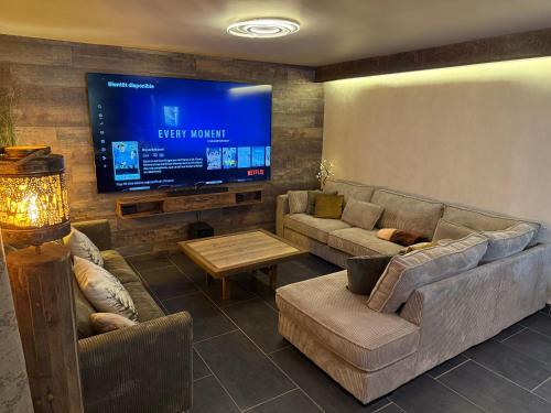 a living room with couches and a flat screen tv at L'écrin de la forêt in Jeanménil