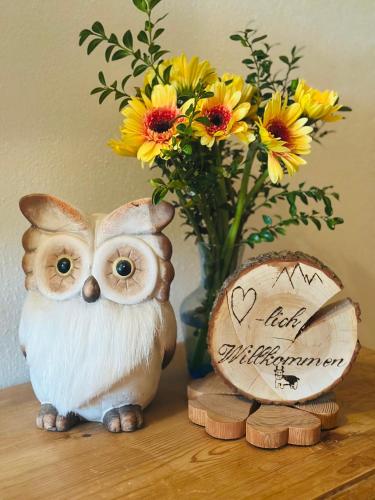 an owl figurine next to a vase with flowers at Ferienwohnung Beim Raffner in Ruhpolding