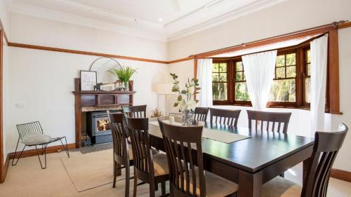 a dining room with a table and chairs and a fireplace at Bali Huts Escape in Nowra