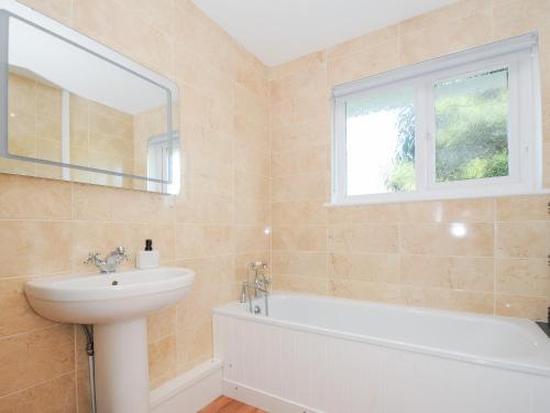 une salle de bain avec un lavabo et une baignoire et une fenêtre dans l'établissement Atlanta, à Tintagel