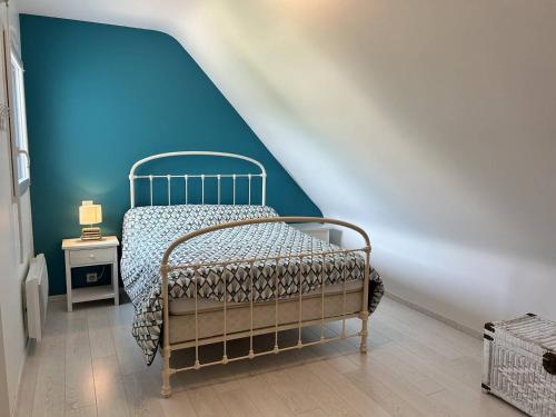 une chambre avec un lit avec un mur bleu dans l'établissement Maison lumineuse, entièrement rénovée, à quelques pas de la plage et des commerces., à Erquy