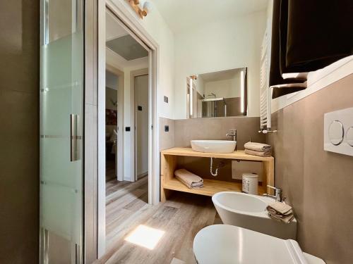a bathroom with two sinks and a toilet and a mirror at Ava home - apartment in the center Camonica Valley in Boario Terme