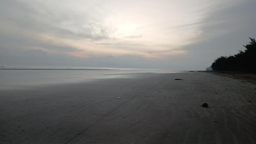 an empty beach with a cloudy sky and the ocean at Ang Roxy Apartment B in Sematan