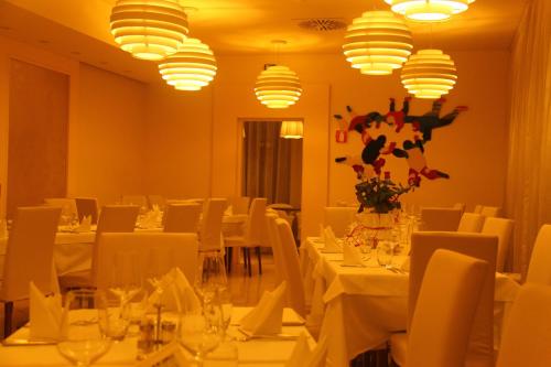 a restaurant with white tables and white chairs and lights at Hotel Touring in Fiorano Modenese