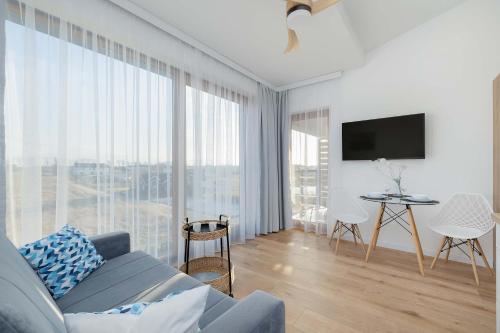a living room with a couch and a large window at Modern & Spacious Apartments Baltin Blu by Noclegi Renters in Sarbinowo