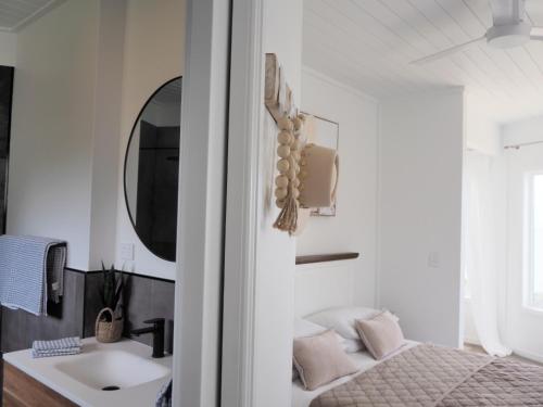 a bathroom with a sink and a mirror and a bed at Tangalooma Life - 2 Bed 2 Bath Private Luxury Stay in Tangalooma