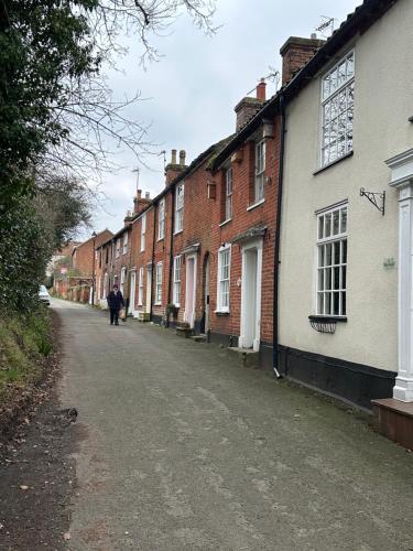 a person walking down a street next to houses at Valentine Cottage, Aylsham in Aylsham