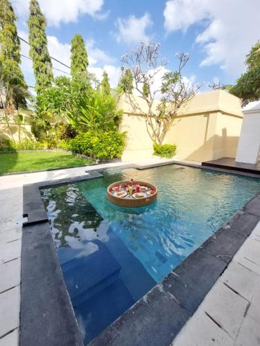 a swimming pool with a boat in the water at The Tukad Villa in Seminyak