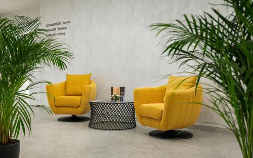 two yellow chairs in a room with plants at Hunguest Hotel Flóra in Eger