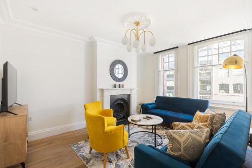 a living room with a blue couch and yellow chairs at HAFH in Farringdon- Stylish 1Bedroom Apartments in London