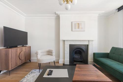a living room with a green couch and a television at HAFH in Farringdon- Stylish 1Bedroom Apartments in London