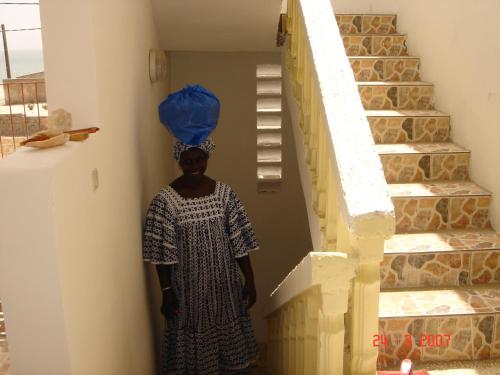 a woman standing next to a staircase with a blue balloon at La Femme Noire in Joal-Fadiout