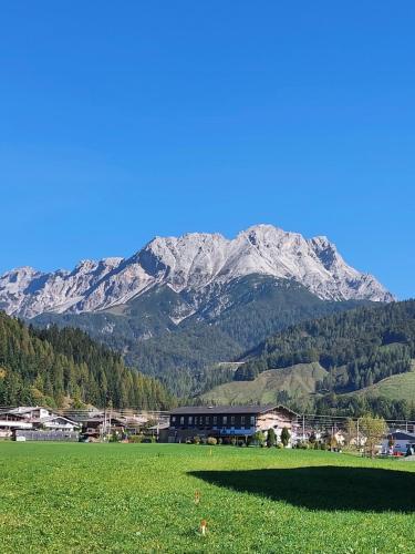 a mountain in the distance with a field and a building at Ferienwohnungen Recherhof in Hochfilzen