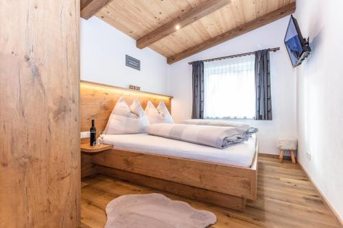 a bedroom with a bed with a wooden headboard and a window at Ferienwohnungen Recherhof in Hochfilzen