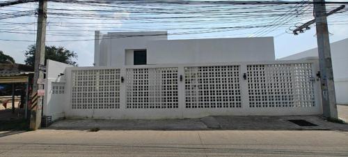 a white fence in front of a white house at Modern Villa with Big Jacuzzi Lets Relax at City LRP4 in Nong Prue
